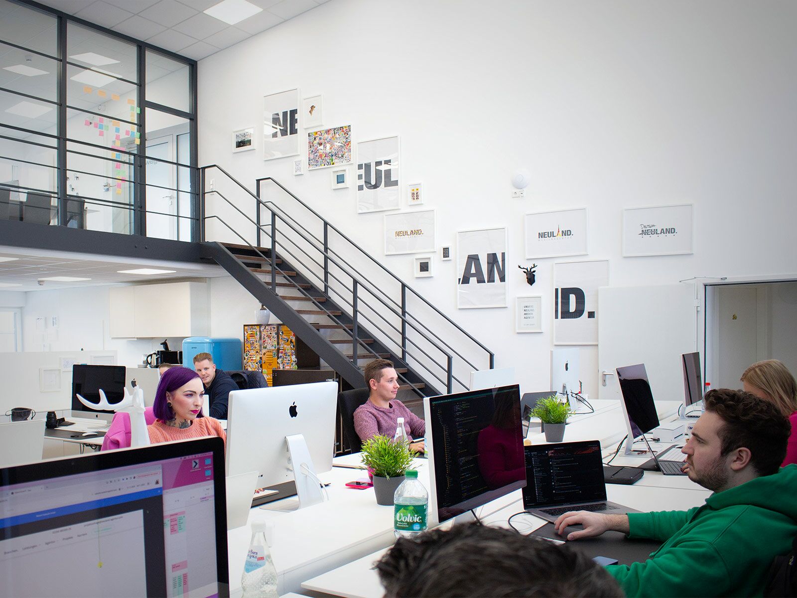 Lösungen | NEULAND. GmbH Eine Gruppe von Personen arbeitet in einem Büro einer B2B-Werbeagentur.